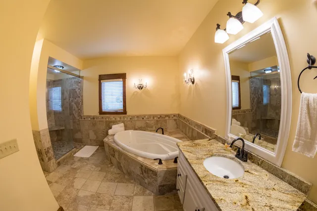 a bathroom with a granite countertop tub sink and mirror
