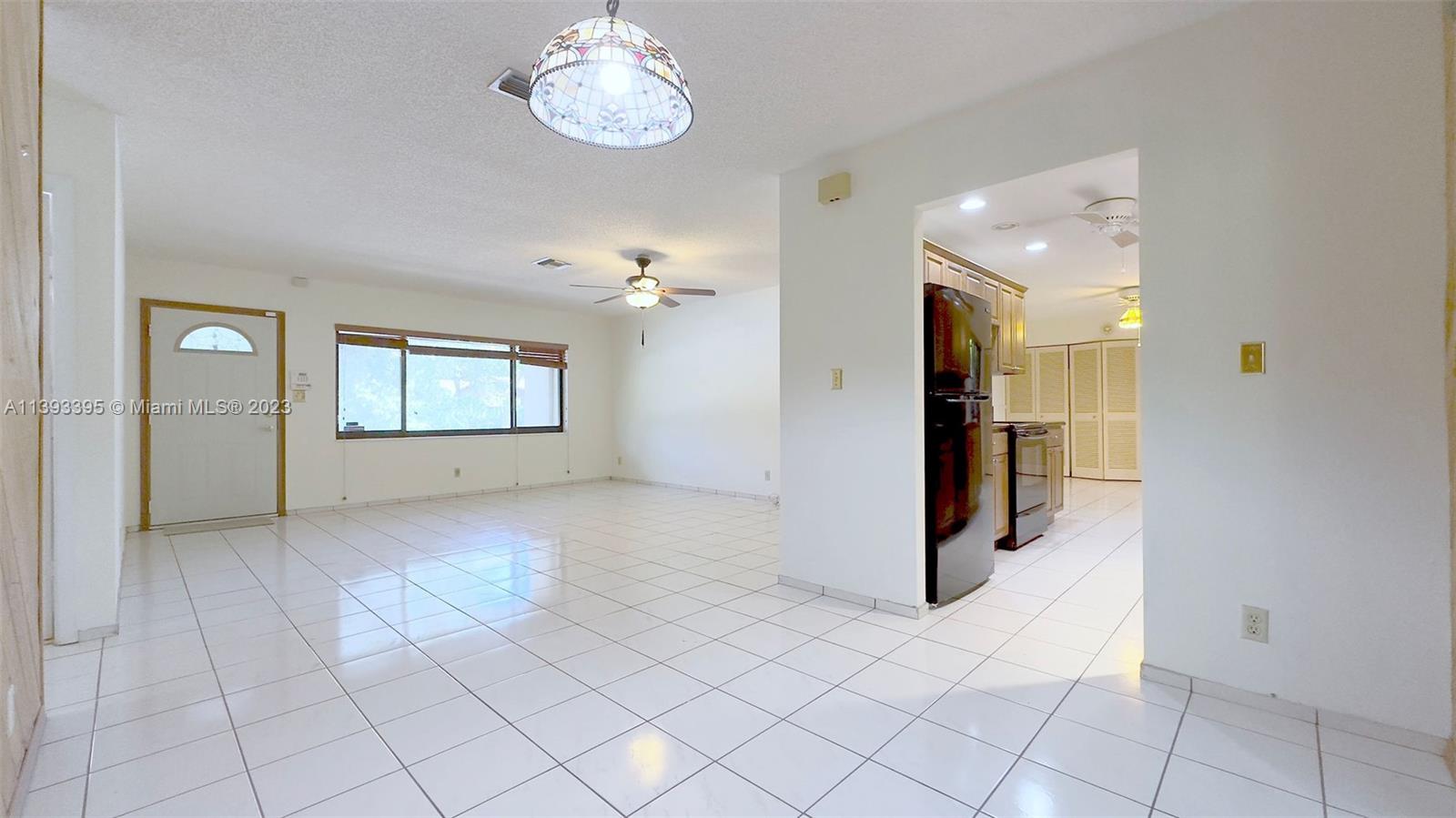 11412 Southwest 113th Place Miami, FL 33176 - Photo 6 of 16 an empty room with kitchen and chandelier fan