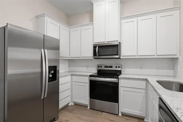 a kitchen with white cabinets and stainless steel appliances