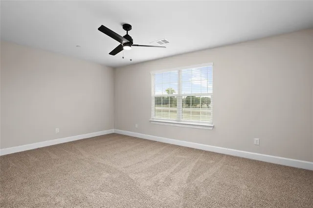 an empty room with ceiling fan and windows