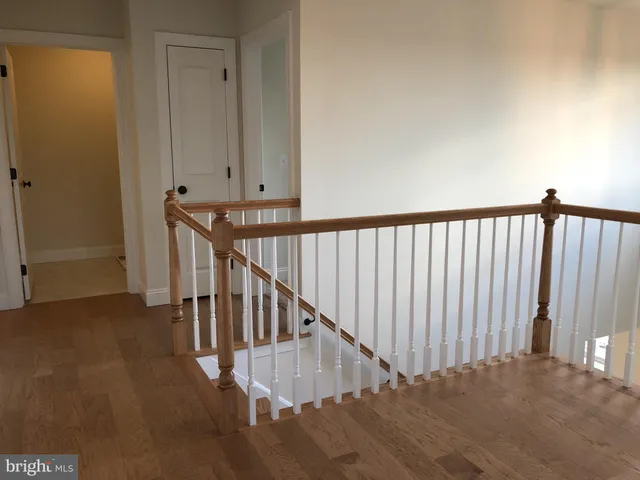 a view of a hallway with wooden floor and stairs