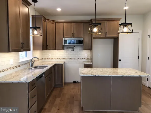 a kitchen with kitchen island granite countertop wooden cabinets and refrigerator