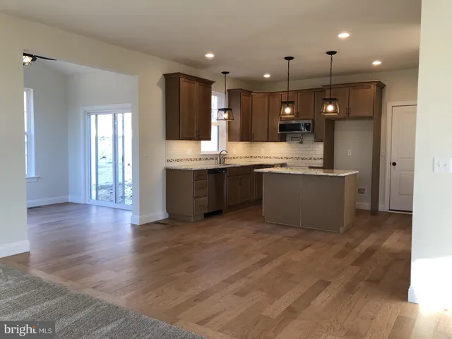 a large kitchen with stainless steel appliances granite countertop a sink and a wooden floors