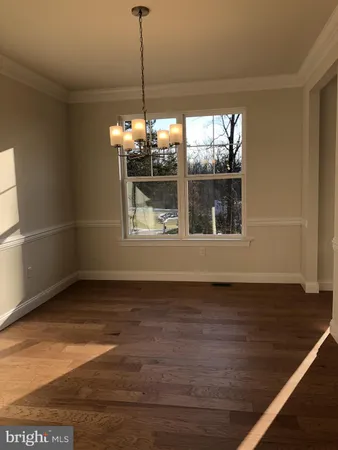 a view of a room with wooden floor chandelier and windows