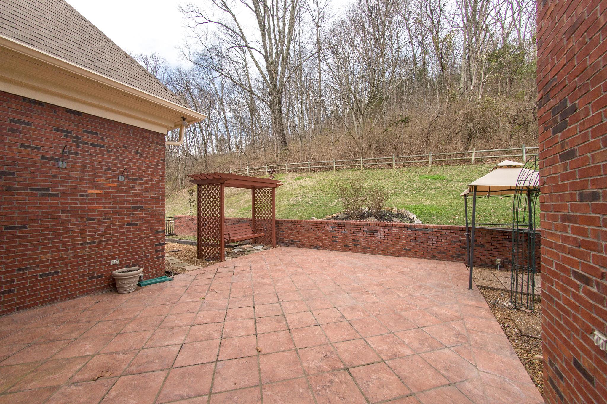 1026 Holly Tree Gap Road Brentwood, TN 37027 - Photo 21 of 27 a view of a backyard with brick wall and potted plants