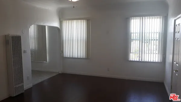 an empty room with wooden floor closet and windows