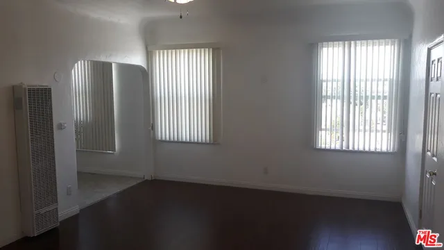 an empty room with wooden floor closet and windows