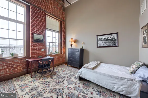 a spacious bedroom with a bed and wooden floor