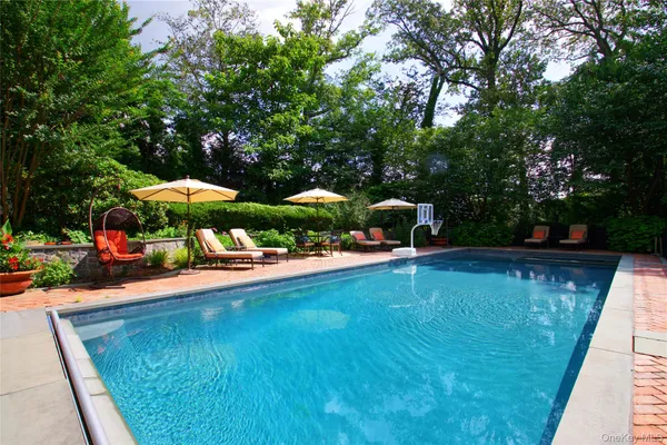 a view of a swimming pool with lawn chairs under an umbrella
