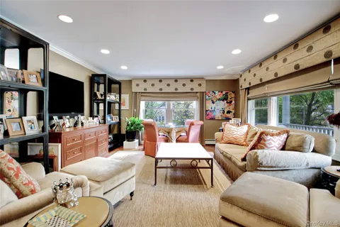 a living room with furniture flat screen tv and floor to ceiling window
