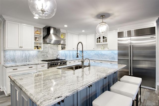 a kitchen with stainless steel appliances granite countertop a sink a stove and a refrigerator