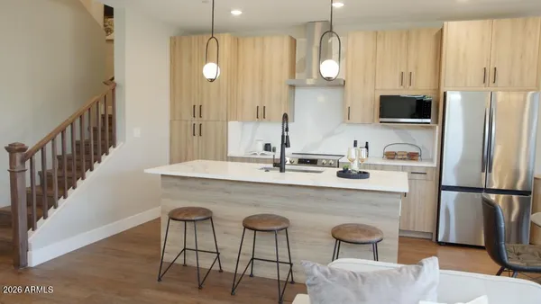a kitchen with stainless steel appliances a dining table chairs sink and refrigerator