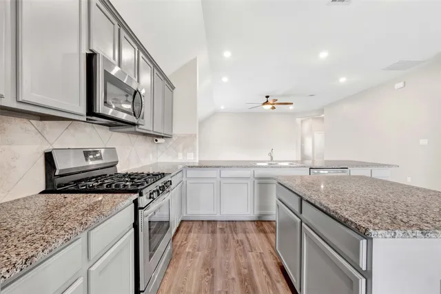a kitchen with stainless steel appliances granite countertop a sink stove and cabinets