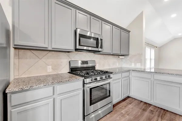 a kitchen with granite countertop wooden cabinets stainless steel appliances and a sink