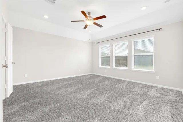 an empty room with ceiling fan and window