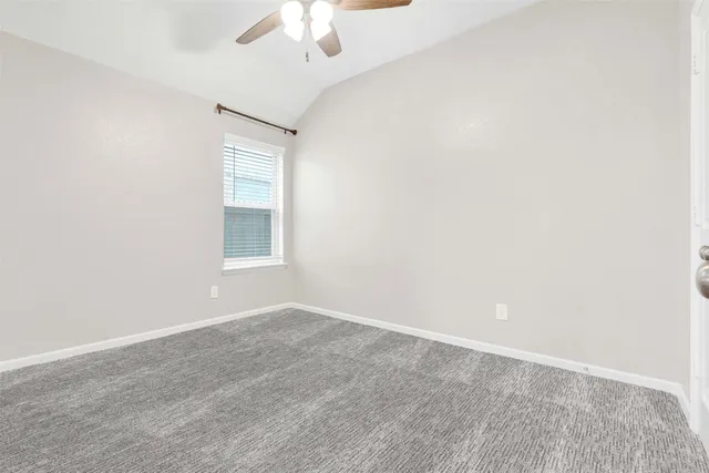 an empty room with a chandelier fan and windows