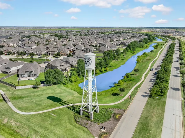 an aerial view of a residential houses with outdoor space and trees