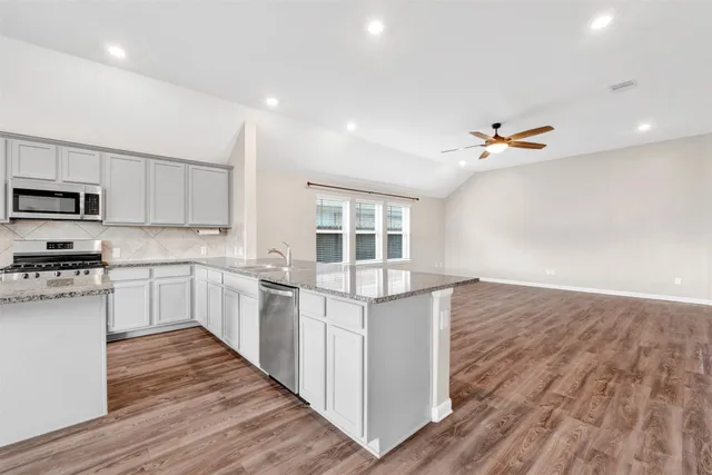a kitchen with stainless steel appliances white cabinets and wooden floor