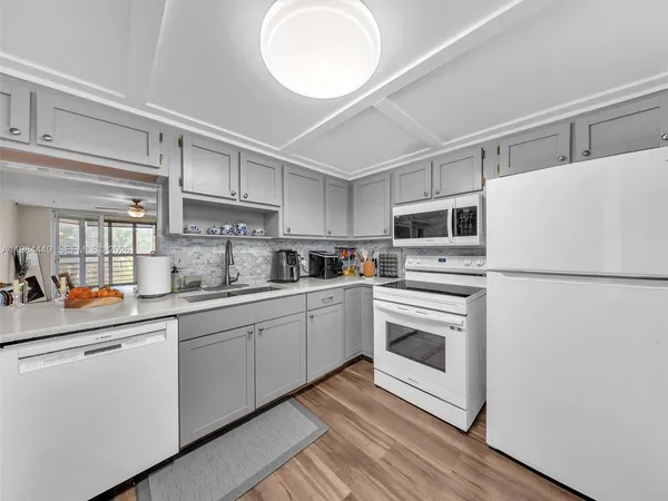 a kitchen with granite countertop appliances a sink and a refrigerator