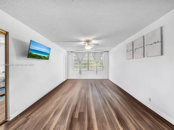 a view of an empty room with wooden floor and a window