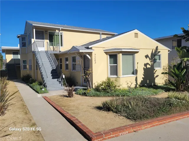 a view of a white house with large windows next to a yard