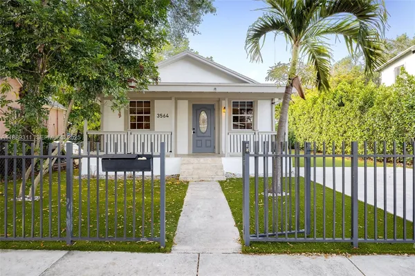 a view of a house with a small yard plants and large trees