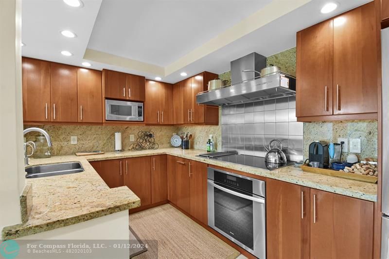 a kitchen with stainless steel appliances granite countertop a sink stove refrigerator and cabinets