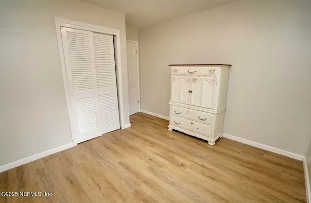 an empty room with wooden floor and cabinet
