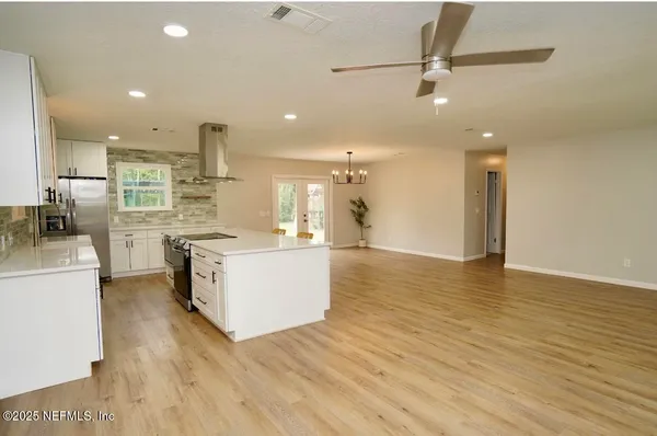 a large kitchen with stainless steel appliances kitchen island a large counter top and a wooden floors