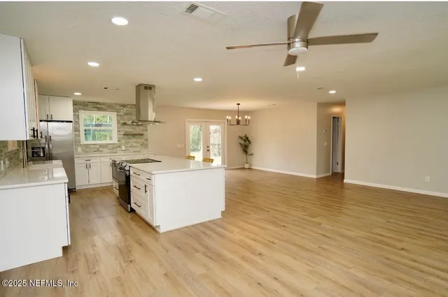 a large kitchen with stainless steel appliances kitchen island a large counter top and a wooden floors