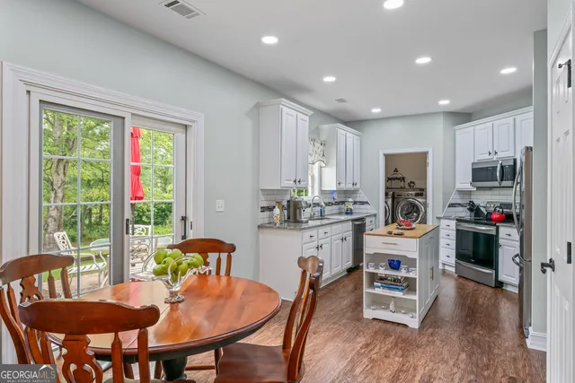 a kitchen with stainless steel appliances granite countertop a stove a refrigerator a kitchen island a table and chairs