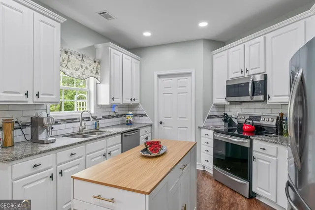 a kitchen with a sink cabinets and flat screen tv