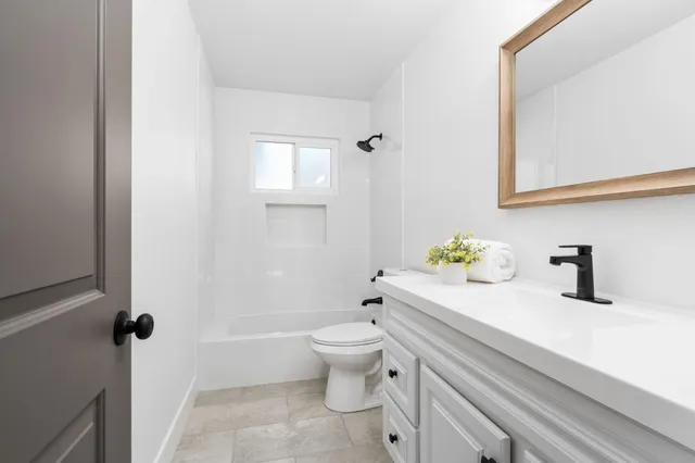 a bathroom with a granite countertop toilet a sink and a mirror