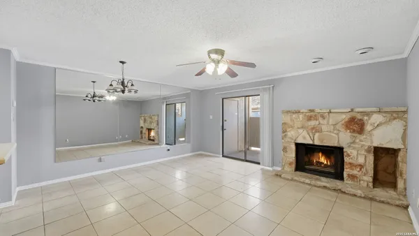 a view of an empty room with fireplace and fan