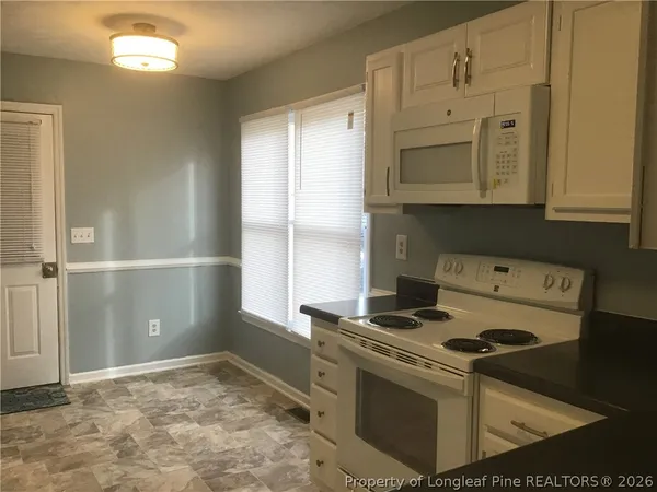 a kitchen with granite countertop a stove a sink and a refrigerator