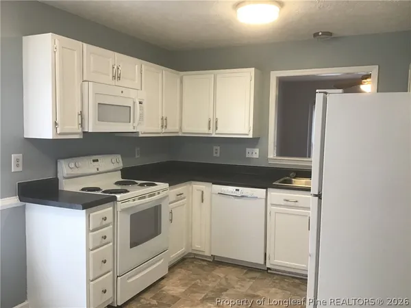 a kitchen with white cabinets and white appliances