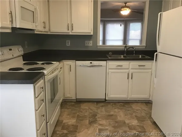 a kitchen with white cabinets and sink