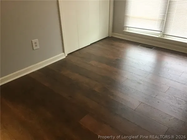 an empty room with wooden floor and windows