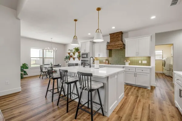 a kitchen with stainless steel appliances granite countertop wooden floors stove and white cabinets