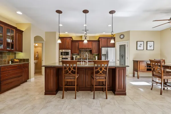 a open kitchen with stainless steel appliances granite countertop a stove top oven a sink a dining table and chairs