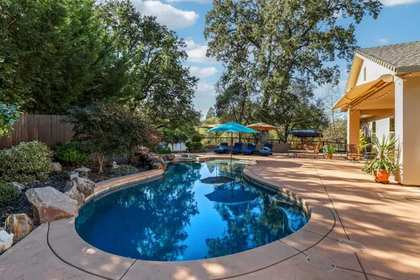 a view of a swimming pool with lawn chairs under an umbrella