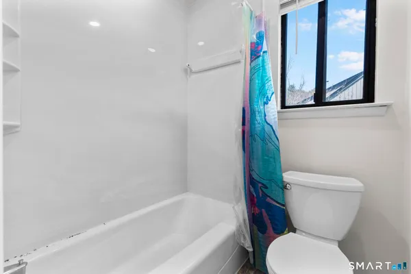 a white toilet sitting next to a bath tub