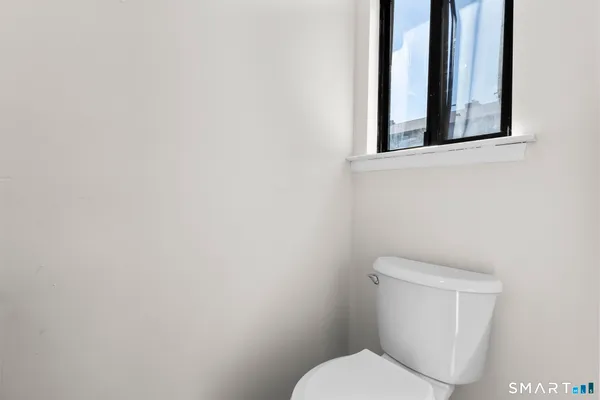 a white toilet sitting next to a white wall