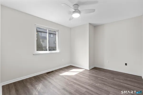 a view of empty room with wooden floor and fan
