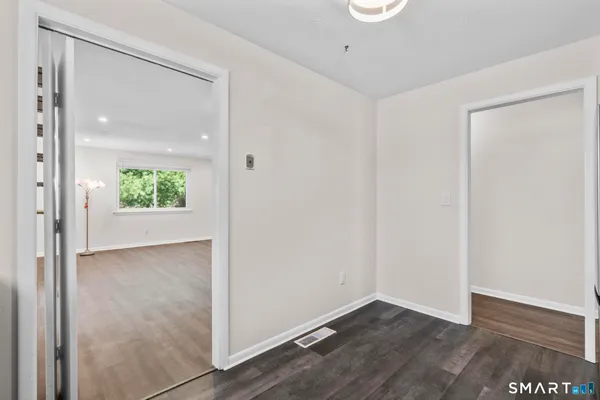 an empty room with wooden floor mirror and windows