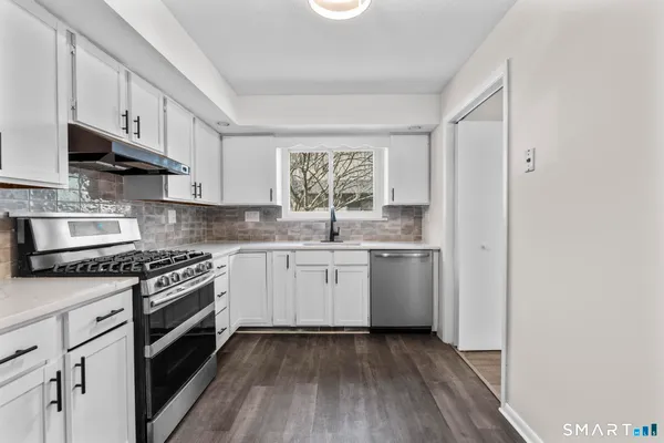 a kitchen with appliances cabinets and a wooden floor