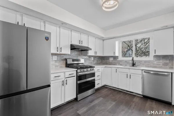 a kitchen with granite countertop white cabinets white stainless steel appliances and sink