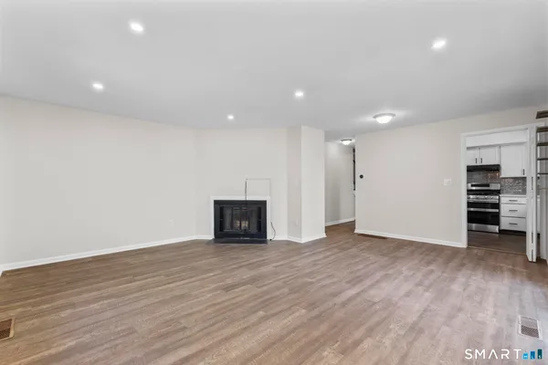 a view of an empty room with wooden floor and closet
