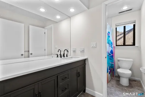 a bathroom with a sink a toilet a mirror and shower