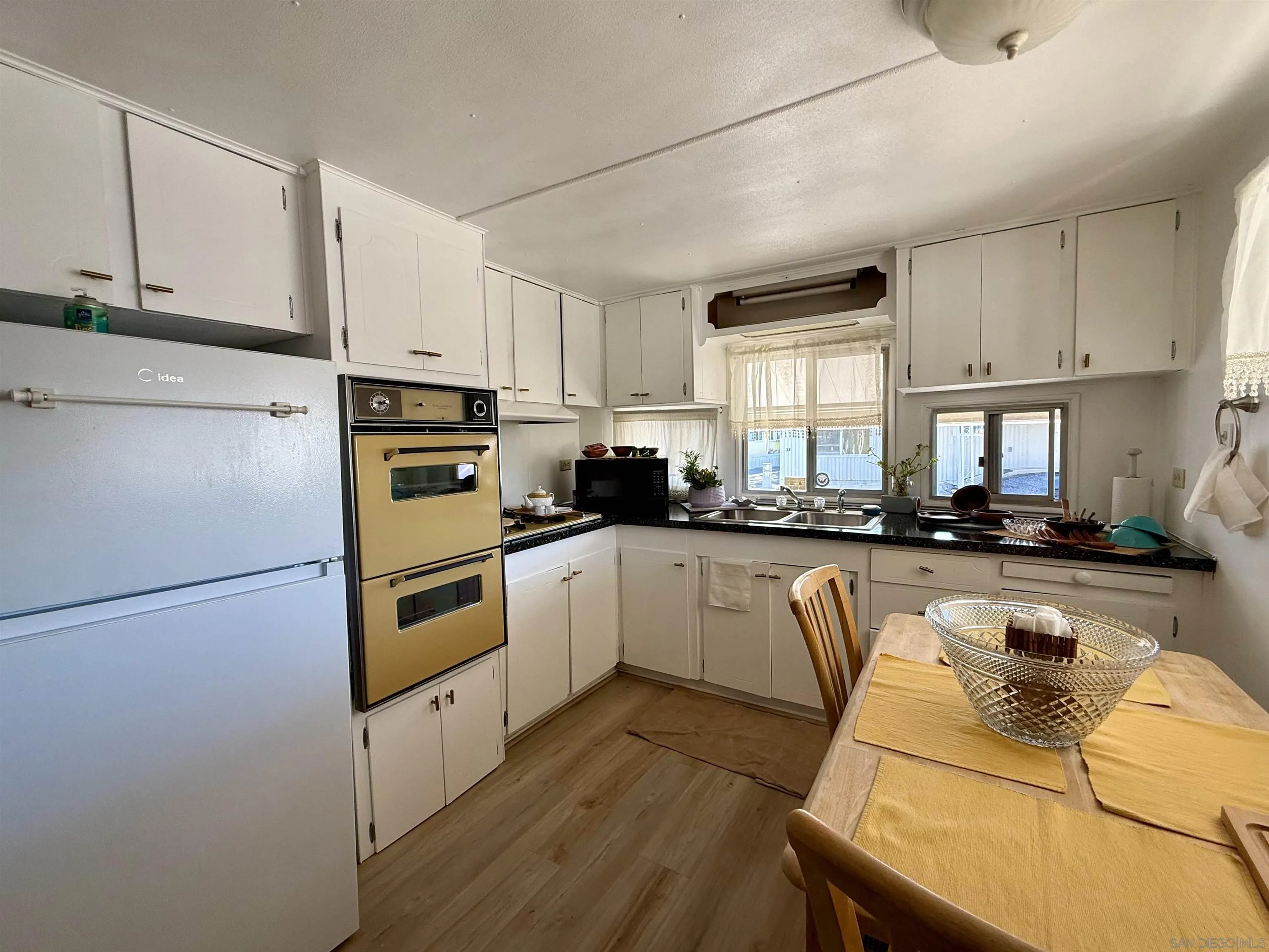 1174 East Main Street El Cajon, CA 92021 - Photo 11 of 23 a kitchen with stainless steel appliances granite countertop a refrigerator a sink dishwasher a stove top oven a refrigerator with white cabinets and wooden floor